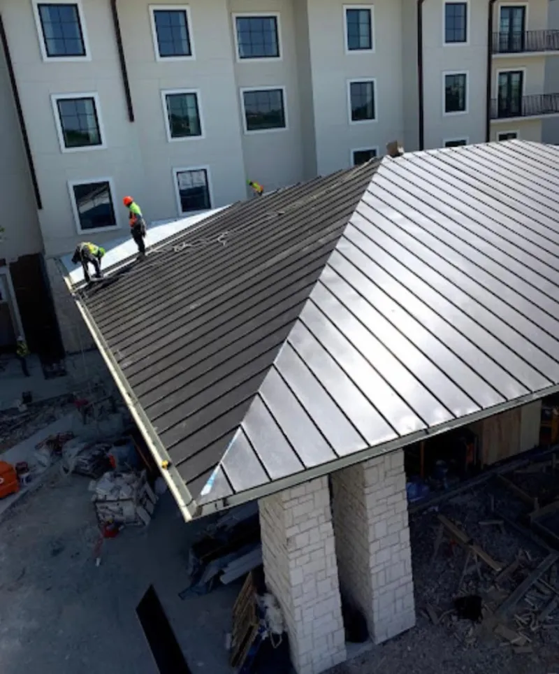 Crew installing standing seam metal roof panels on a commercial project in Coldwater